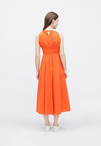 Oranžové midi šaty s priliehavým pásom, nariaseným chrbtom a výrezom na krku v tvare kľúčovej dierky. Hladká látka s voľnou sukňou.