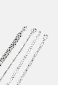 Set de lanț din metal argintiu cu designuri variate: inele groase, inele ovale subțiri și inele dreptunghiulareîntinse, toate cu închideri sigure.