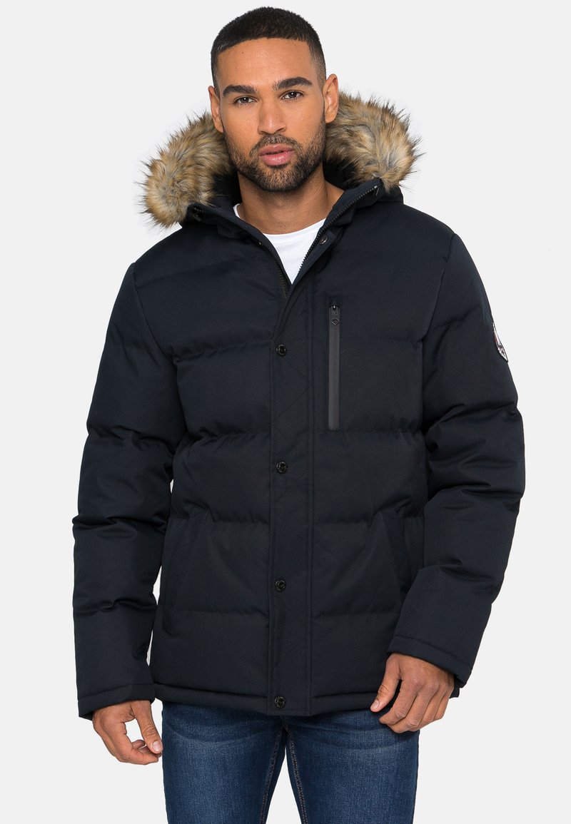 Marineblaue Steppjacke mit Kapuze aus Kunstfell, isolierendem gestepptem Design, durchgehendem Knopfverschluss und einer seitlichen Reißverschlusstasche.