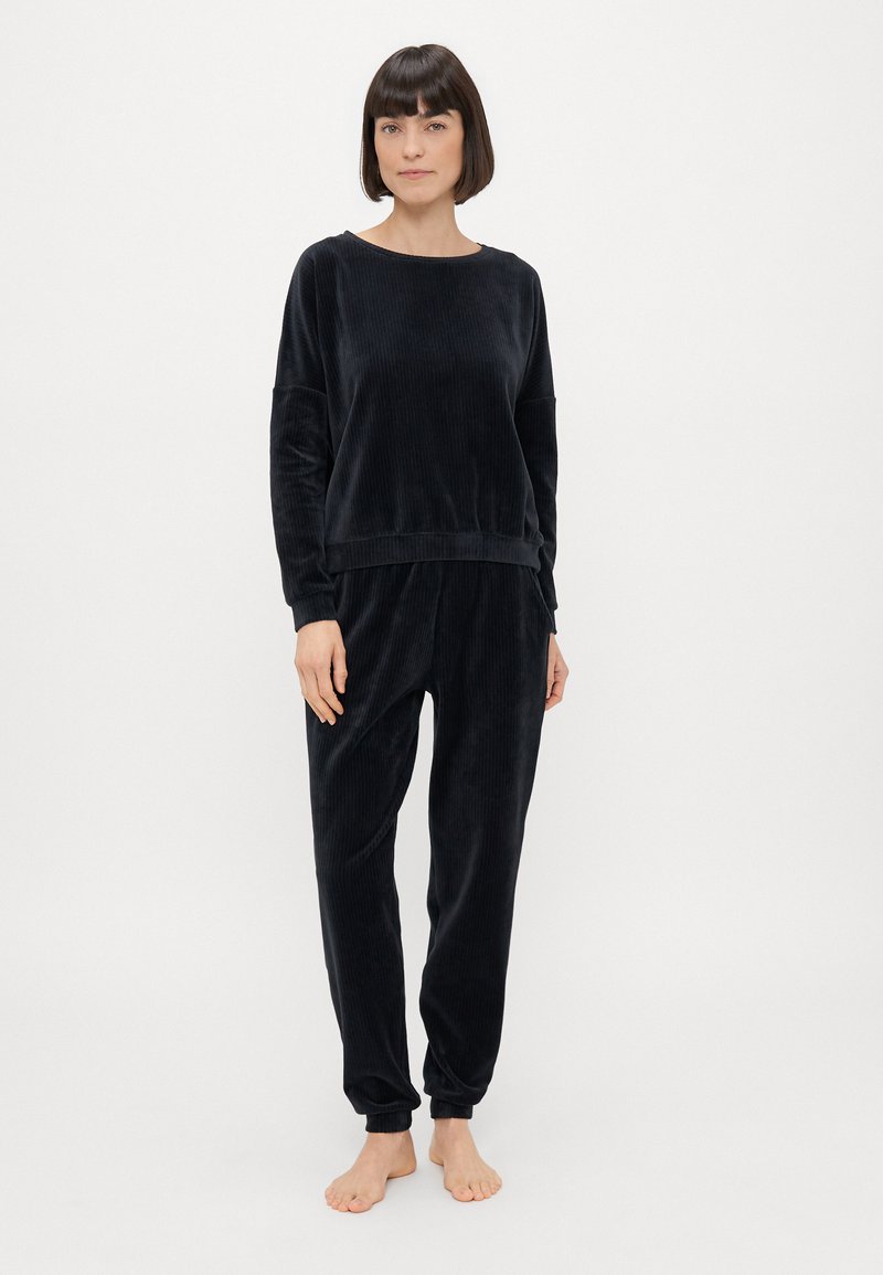 Μαύρο σετ λυχνιστικού ρουχισμού από βελούδο με μακρυμάνικη μπλούζα με στρογγυλή λαιμόκοψη και tapered παντελόνι. Ριπ ύφανση με χαλαρή εφαρμογή. Χωρίς ορατά σχέδια ή διακοσμητικά στοιχεία.