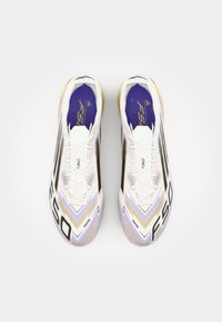 White soccer cleats with black and purple accents, featuring a sleek design, textured surface, and "F50" branding on the sides.