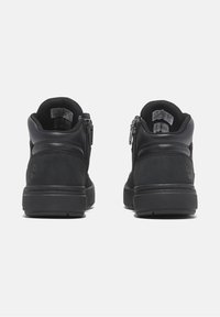 Czarne buty typu mid-top z gładkiej i teksturowanej skóry, z bocznymi zamkami błyskawicznymi, okrągłym noskiem, wyściółką z kołnierzem oraz grubą gumową podeszwą.