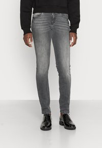 Grå denimjeans i slim fit med en blekt tvätt, framfickor och dragkedja. Stylad med blanka svarta skor.