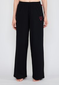 Mustat leveälahkeiset housut pehmeästä kankaasta, jossa on joustava vyötärönauha ja punainen "JOOP! JEANS" -logo lantiolla.