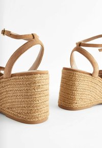 Braune Wildleder-Wedgesandalen mit einem strukturierten Seildesign an der Ferse. Mit Riemen um den Knöchel und einer glatten Fußbett.