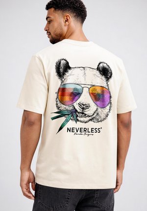 Man wearing cream t-shirt with large panda face wearing colorful aviator sunglasses and bamboo stalks graphic on the back.