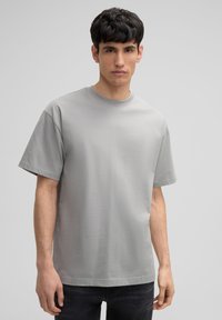Grijze, kortemouwen t-shirt van gladde stof met een ronde hals en een losse pasvorm, met een eenvoudige uitstraling zonder patronen of accenten.