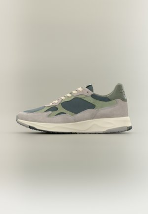 Niskie tenisówki z beżowego zamszu, zielonymi panelami z siateczki, kremowymi sznurowadłami i grubą białą podeszwą na neutralnym tle.