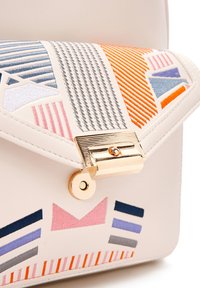 Sac structuré en cuir beige doux, orné de broderies géométriques colorées et d'un fermoir doré. Les accents incluent des motifs variés en orange, bleu et rose.