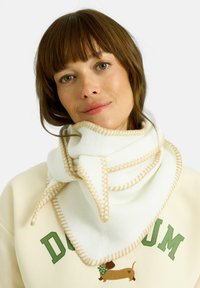 Bufanda de forro polar blanca con costuras beige, diseño triangular, envuelta alrededor del cuello, mostrando textura suave y apariencia estratificada.