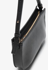 Black leather handbag with a smooth texture, gold zipper, and an adjustable strap featuring snap fasteners and multiple holes for length adjustment.