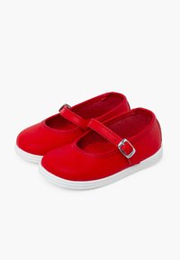 Zapatos Mary Jane de cuero rojo con una suela de goma blanca, que cuentan con una correa con hebilla plateada y una puntera redondeada. Textura suave.