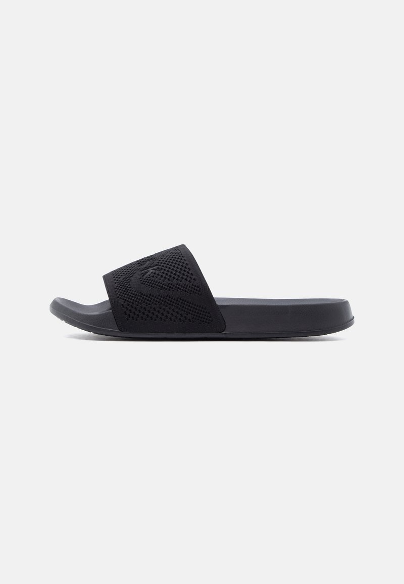 Μαύρο σανδάλι τύπου slip-on με φαρδιά υφή λουράκι και επίπεδη σόλα, εμφανίζεται σε πλαϊνή όψη σε απλό ανοιχτό φόντο.