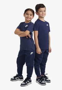 T-shirt e pantaloni Nike blu navy con loghi bianchi, vestibilità rilassata, in cotone, abbinati a sneakers Nike nere e grigie.