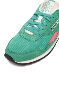 Sneaker in suede verde e mesh con superficie strutturata, accento rosa a contrasto e lacci turchesi. Presenta una intersuola bianca e una suola nera.