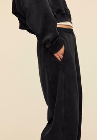 Sort oversized sweatshirt med cropped design og ribstrikkede manchetter, kombineret med matchende sorte sweatpants med sidelommer.