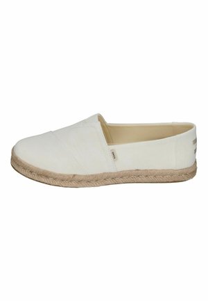 Chaussure blanche à enfiler en toile avec semelle enveloppée de jute et petite étiquette en tissu près de l'ouverture, vue de côté.