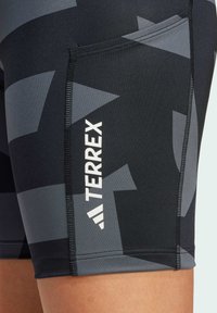 Čierne a šedé atletické šortky s geometrickým vzorom, so bočnou kapsou a bielym logom "TERREX" pri dolnom leme.