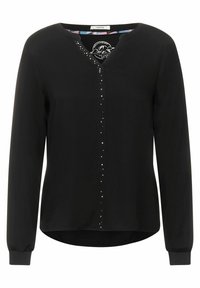 Schwarze Bluse mit langen Ärmeln, V-Ausschnitt und dekorativen Nieten entlang der Mitte. Verfügt über elastische Bündchen und einen geschwungenen Saum. Weicher Stoff.