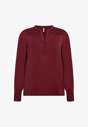 Burgundy pitkähihaine paita pyöreällä kauluksella, kolmella napilla, kuositeltu yksityiskohta harteilla ja kerätyt hihansuut. Pehmeä materiaali.