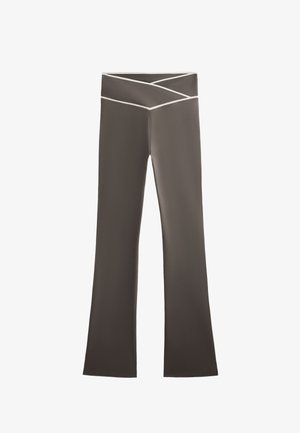 Hnedé rozšírené nohavice s širokým pásom, ktorý má krížový vzor a biele akcentové stehy. Hladká textúra látky, bez viditeľných vreciek.