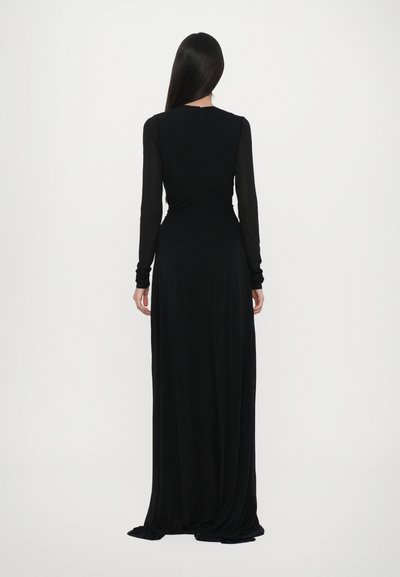 Vestido negro de manga larga, ajustado en la cintura con una falda fluida. Hecho de un tejido suave con una textura lisa, con un diseño simple.