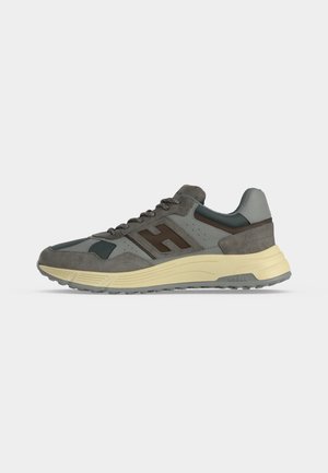 Baskets gris et vert foncé avec des accents marron et une semelle beige clair, montrant un profil latéral sur un fond clair uni.
