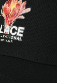 Gorra negra con un diseño gráfico floral en rojo y naranja, y texto blanco que dice "WALLACE INTERNATIONAL ORIGINALS."