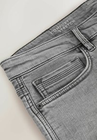 Blugi gri din denim, cu funcție de întindere pentru confort, având un design cu cinci buzunare, cusături subtile și o textură netedă și elegantă.