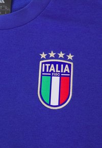 Blå skjorte med brodert nasjonal fotballlagmerke fra Italia, som har fire gullstjerner og vertikale striper i grønt, hvitt og rødt.