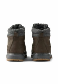 Botas de cuero marrón con puño de fieltro gris, forma redondeada, superficie texturizada y suela de goma de contraste. Cuenta con un bucle en la parte trasera para facilitar su uso.