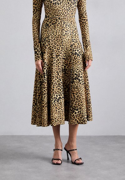 Rochie cu imprimeu leopard, cu mâneci lungi și tiv evazat, realizată dintr-un textil neted. Prezintă un corset ajustat și este purtată cu sandale negre cu bretele.