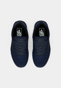 Granatowe trampki Vans z materiału zamszowego i kanwowego, płaskimi sznurówkami, wyściełanym językiem oraz akcentami logo na języku i boku.