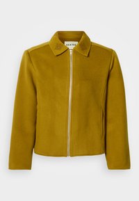 Jopič v gorčično rumeni barvi, izdelan iz mehkega blaga, z zadrgo spredaj, ovratnikom in cvetličnim vezenjem na ovratniku. Raven kroj s stranskimi žepi.