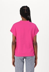 Kortermet, lys rosa bomull T-skjorte med rund hals og avslappet passform, kombinert med lysegrå denimjeans. Enkel og uformell design.