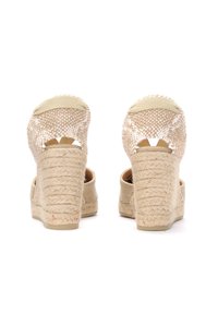 Sandali a zeppa beige con tacco in juta intrecciata. Design con retro aperto, tomaia in tessuto texturizzato con dettaglio a motivi e soletta imbottita.
