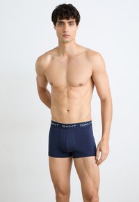Marineblaue Boxershorts aus weichem Material, mit einem kontrastierenden Bund, auf dem der Markenname "GANT" deutlich sichtbar ist.