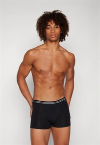 Fekete boxeralsó testhez simuló fazonban, kontrasztos fehér derékrésszel. Simogató anyag és egyszerű dizájn, alkalmas mindennapi viseletre.