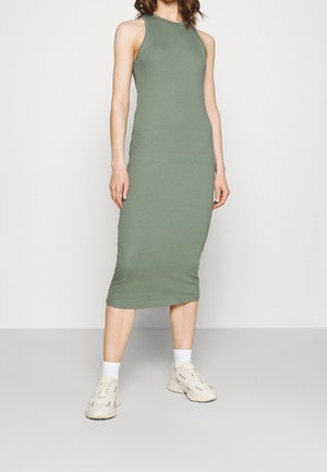 Ribbed midi dress w stonowanym zielonym kolorze, z wysoką gardą i dopasowanym krojem. Zestawiona z białymi skarpetkami i beżowymi sneakersami. Gładka tekstura.