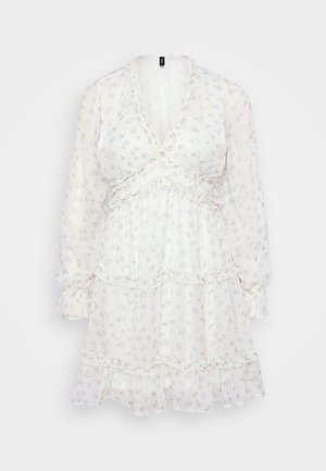 Vit blommig klänning med långa ärmar, volanglager och V-utsättning. Har små blå blommor på ett genomskinligt tyg för en lätt textur.
