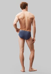 Slip in cotone blu navy con vita elasticizzata, caratterizzati dal logo bianco "Calvin Klein", vestibilità aderente e senza motivi o accenti visibili.