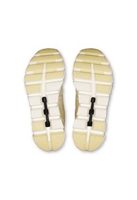 Suelas de zapatos deportivos de color claro con un patrón texturizado. Incluyen ranuras para mayor agarre y un detalle de placa negra en el centro.