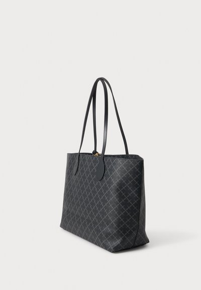 Sac fourre-tout noir avec de longues anses et un motif en losanges subtil, debout sur un fond clair uni.