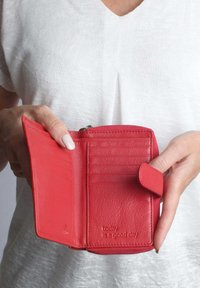 Rote Lederbörse mit mehreren Kartenfächern, einem Reißverschlussfach und geprägtem Text, der "Heute ist ein guter Tag" lautet. Strukturierte Oberfläche.