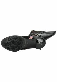 Stivaletto nero con sovrapposizione in tessuto floreale, punta appuntita e accessori decorativi. La suola in gomma testurizzata presenta un intricato motivo floreale. Taglia 37.