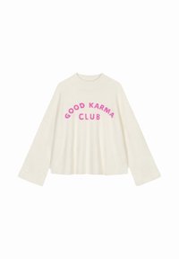 Crème-kleurige, oversized trui met brede mouwen. Bevat de tekst "GOOD KARMA CLUB" in vetgedrukte, fuchsia letters op de borst.