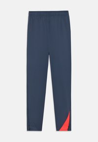 Pantalons de sport bleu marine avec une taille élastique, présentant des accents rouges au niveau des poignets et des zippers latéraux. Tissu lisse avec un design fuselé.