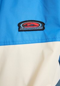 Μπλέ και κρεμ σακάκι με υφή και οριζόντια χρωματικά μπλοκ. Περιέχει λογότυπο "BangingBees" κεντημένο σε μαύρο.