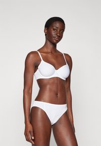 Hvit polstret BH med justerbare stropper og matchende hvite bikini-truser. Glatt stoff, minimalistisk design og god passform.