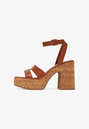 Pruunid kunstnahast platvormsandaalid korkkontsadega, ristsitatud rihmadega ja reguleeritava pahkluu rihmaga, millel on ristkülikukujuline pandla.